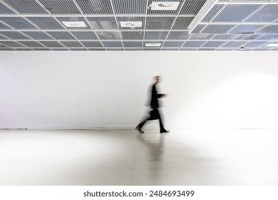 a blurred silouhette of business man walk in a white corridor - Powered by Shutterstock