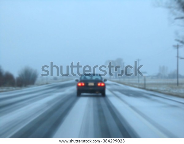 A blurred single car running\
on country road covered with white snow in January at Colorado\
USA