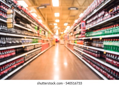 Blurred Soft Drinks Aisle In American Store. The Affordability, Wide Variety Of Sugary Drink Contribute To The Growing Obesity Problem In U.S. Fuzzy Drink Bottles Display On Shelves, Customer Shopping