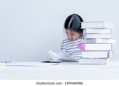 Blurred Soft Images Of A 6 Year Old Asian Girl Sitting Reading A Textbook Whit Determination, On White Background, Concept To Children And Education. This Picture Focuses On The Stack Of Books.