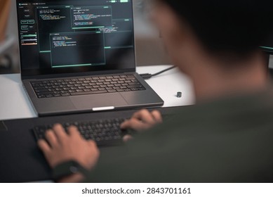Blurred software developer writing code on a laptop in a dark workspace focused on artificial intelligence programming and advanced technology development