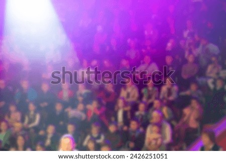 Blurred spectators in a circus or at a performance in a purple stage light.