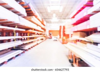 Blurred Stack New Wooden Bar On Shelves Inside Lumber Yard Of Large Hardware Store In America. Rack Of Fresh Mill/cut Wood Timber With Flatbed Cart, Manual Forklift In Warehouse. Industrial Background