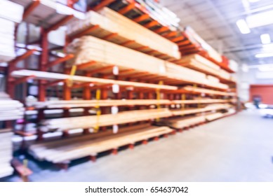 Blurred Stack New Wooden Bar On Shelves Inside Lumber Yard Of Large Hardware Store In America. Rack Of Fresh Mill/cut Wood Timber With Flatbed Cart, Manual Forklift In Warehouse. Industrial Background