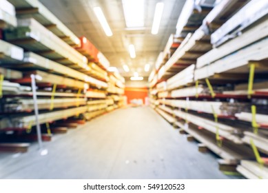 Blurred Stack Of New Wooden Bars On Shelves Inside Lumber Yard Of Large Hardware Store In America. Rack Of Fresh Mill/cut Wood Timber In Warehouse. Industrial And Construction Background. Vintage Tone