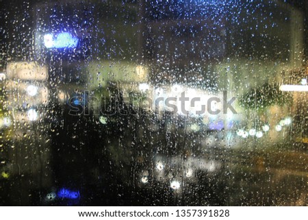 Blurred street lights and illuminated houses, a view from a wet window glass on a rainy night