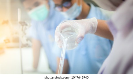 Blurred Student Holding Beaker Pouring 
 Chemical Substance To Burette For Test Chemistry Laboratory In Science Classroom.