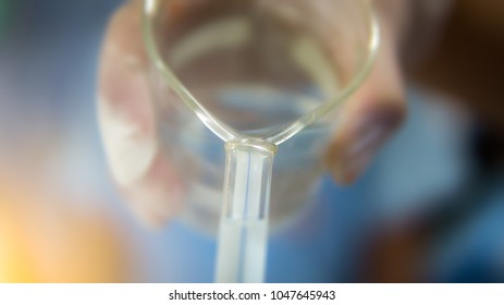 Blurred Student Holding Beaker Pouring 
 Chemical Substance To Burette For Test Chemistry Laboratory In Science Classroom.