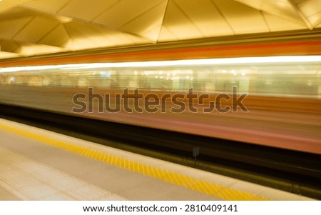 Blurred subway train creating a sense of speed and movement as it passes through an underground station.