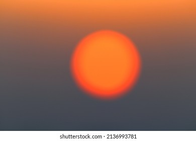 Blurred sun disk between the dark clouds at sunrise