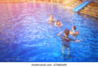 Blurred swimming pool actvity; Asian fathers taking care and teaching their kids to swim; add flare light - Copy space for text on the left. - Powered by Shutterstock