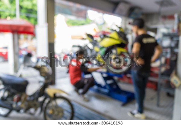 Blurred of technician repairing the\
motorcycle in garage\
background.