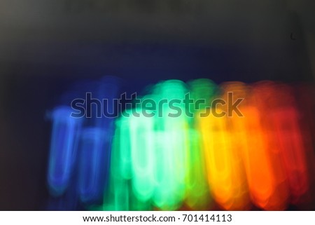 Blurred test-tubes with quantum dots of perovskite nanocrystals luminescing in the dark with all the colors of the rainbow under the influence of ultraviolet radiation