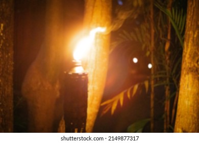 Blurred Torch Flame Against Blurred Jungle Background. A Torch In A Mayan Village At Night, Out Of Focus Photo. The Concept Of Magic And Rituals.