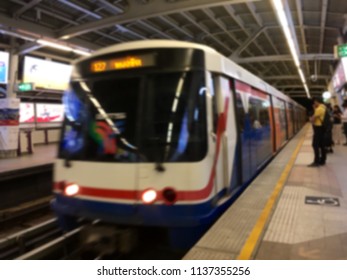 Blurred train come into platform and passenger stand behind yellow line.