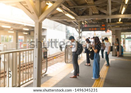 Blurred train station platform - Business man, salaryman, traveler are waiting and standing in line, many looking at smart phone, in the morning. Daily Routine Railway Commute, Japan Urban Lifestyle.