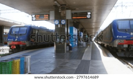 Blurred train station platform with defocused trains, canopy, columns, ticket machines and crates in shallow focus station; background backdrop copyspace backplate.