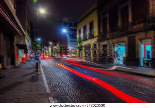 Blurred travel\
backgrounds -  Streets of Mexico City at night, car light trails,\
different shops and bars, dark\
sky