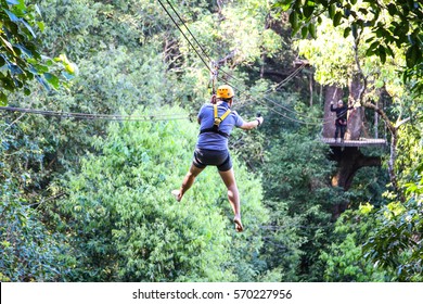 Blurred traveler  hung on a a wire rope over a  forest on a jungle zip line adventure  - Powered by Shutterstock