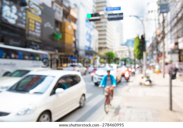 Blurred unfocused city view at day time. Unfocused\
cars in the way. Man on\
bike.