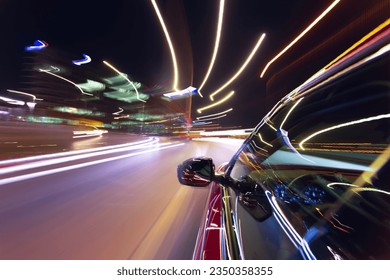 Blurred urban look from fast driving car to back side and driver at summer night. Longexposure shot.