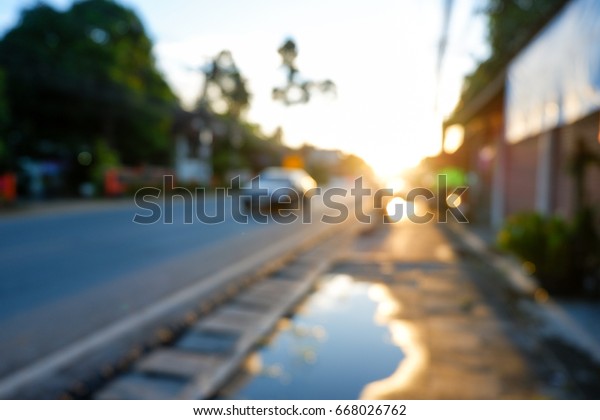 Blurred of urban road in\
sunset after rain with car on road. Use for traffic background\
concept.