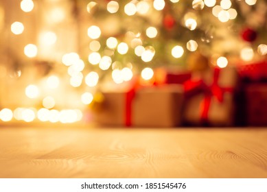 Blurred View Of Christmas Tree In Bright Warm Lights And Beautiful Presents Under It, Focus On The Floor. Festive Atmosphere, New Year Holidays Background.