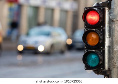 blurred view of city traffic with traffic lights, in the foreground a semaphore with a red light - Shutterstock ID 1910723365