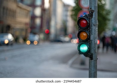 blurred view of city traffic with traffic lights, in the foreground a semaphore with a green light