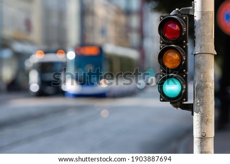 blurred view of city traffic with traffic lights, in the foreground a traffic light with a green light