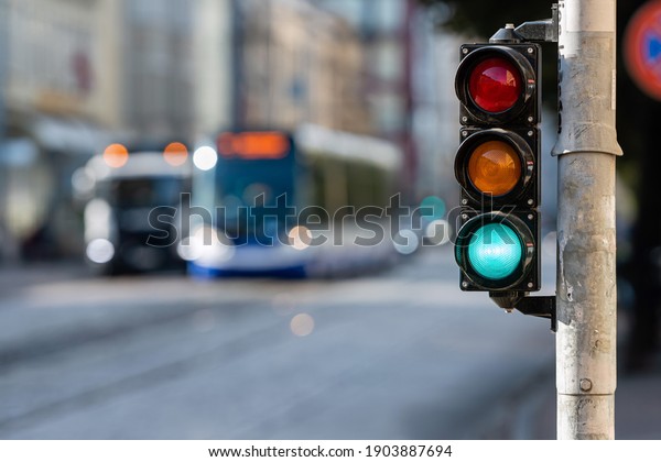blurred view of city\
traffic with traffic lights, in the foreground a traffic light with\
a green light