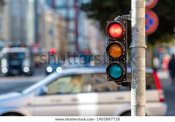 blurred view of city\
traffic with traffic lights, in the foreground a traffic light with\
a red light