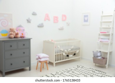 Blurred view of cute baby room interior with modern crib near white wall - Shutterstock ID 1765138433