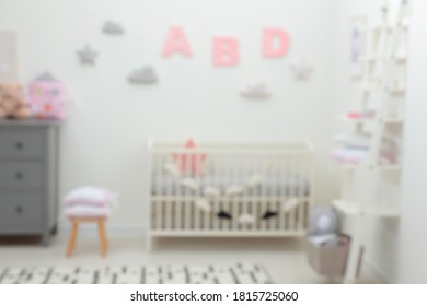 Blurred view of cute baby room interior with modern crib near white wall - Shutterstock ID 1815725060
