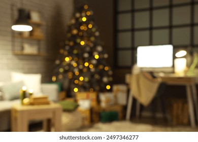 Blurred view of dark programmer's office with workplace and glowing Christmas tree