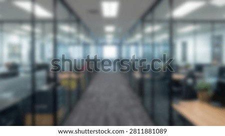 A blurred view down a contemporary office hallway with glass partitions and workstations, suggesting a professional workspace.