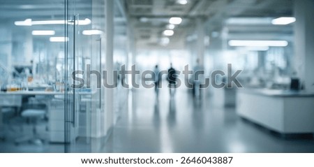 Blurred view down a modern, bright laboratory hallway.  Scientists or researchers are walking away in the distance.  Glass partitions separate lab workspaces.