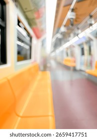 Blurred view of an empty subway train interior with bright yellow seats and stainless steel poles. The modern train car is well-lit, featuring overhead handles and smooth, clean floors