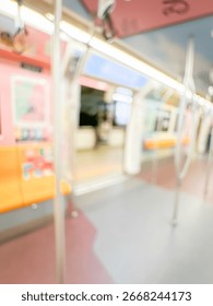 Blurred view of an empty subway train interior with bright yellow seats and stainless steel poles. The modern train car is well-lit, featuring overhead handles and smooth