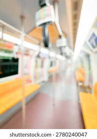 Blurred view of an empty subway train interior with bright yellow seats and stainless steel poles. The modern train car is well-lit, featuring overhead handles and smooth, clean floors, suggesting public transportation in motion.
