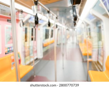 Blurred view of an empty subway train interior with bright yellow seats and stainless steel poles. The modern train car is well-lit, featuring overhead handles and smooth, clean floors, suggesting public transportation in motion.