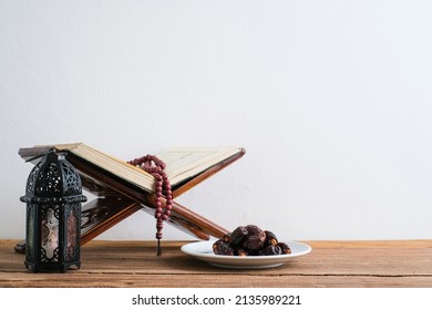 Blurred view of The Holy Al Quran with written Arabic calligraphy meaning of Al Quran and rosary beads or tasbih, Arabic word translation : The Holy Al Quran