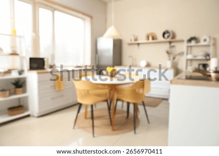 Blurred view of kitchen with dining table, counters and shelf units