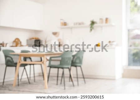 Blurred view of light kitchen with counters, shelf and dining table