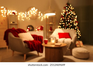 Blurred view of living room with armchairs, Christmas tree and glowing lights at night - Powered by Shutterstock