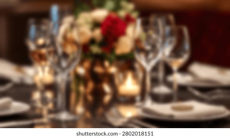 Blurred view of a luxury dinner table set with wine glasses, candles, and flowers.
