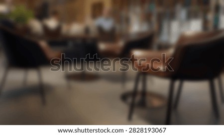 A blurred view of a modern cafe interior with plush chairs and tables, creating a welcoming atmosphere for patrons.