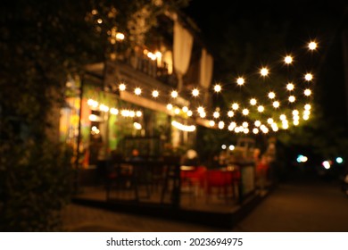 Blurred View Of Modern Cafe With Outdoor Terrace At Night