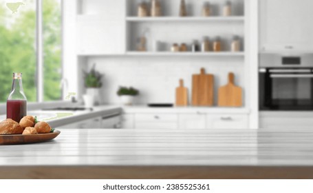 Blurred view of modern kitchen with white furniture with wooden table - Powered by Shutterstock