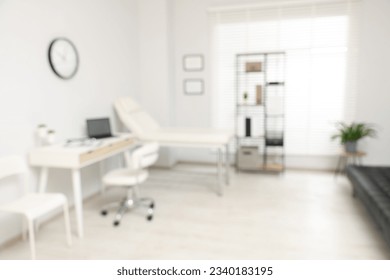 Blurred view of modern medical office with doctor's workplace and examination table in clinic